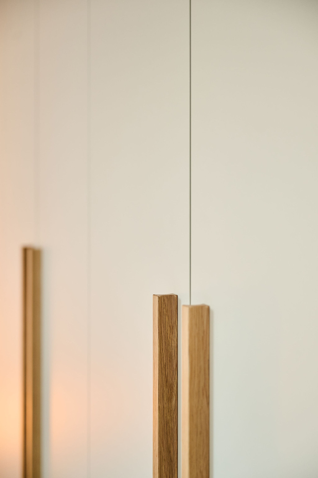 Close-up van verticale houten handgrepen op een beige maatkast met zacht sfeerlicht