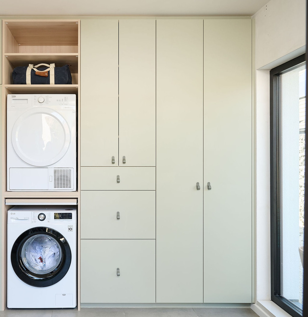 Buanderie Camber sur mesure avec machine à laver et sèche-linge intégrés en colonne, placards fermés sur mesure et espaces de rangement supplémentaires dans un aménagement épuré et fonctionnel