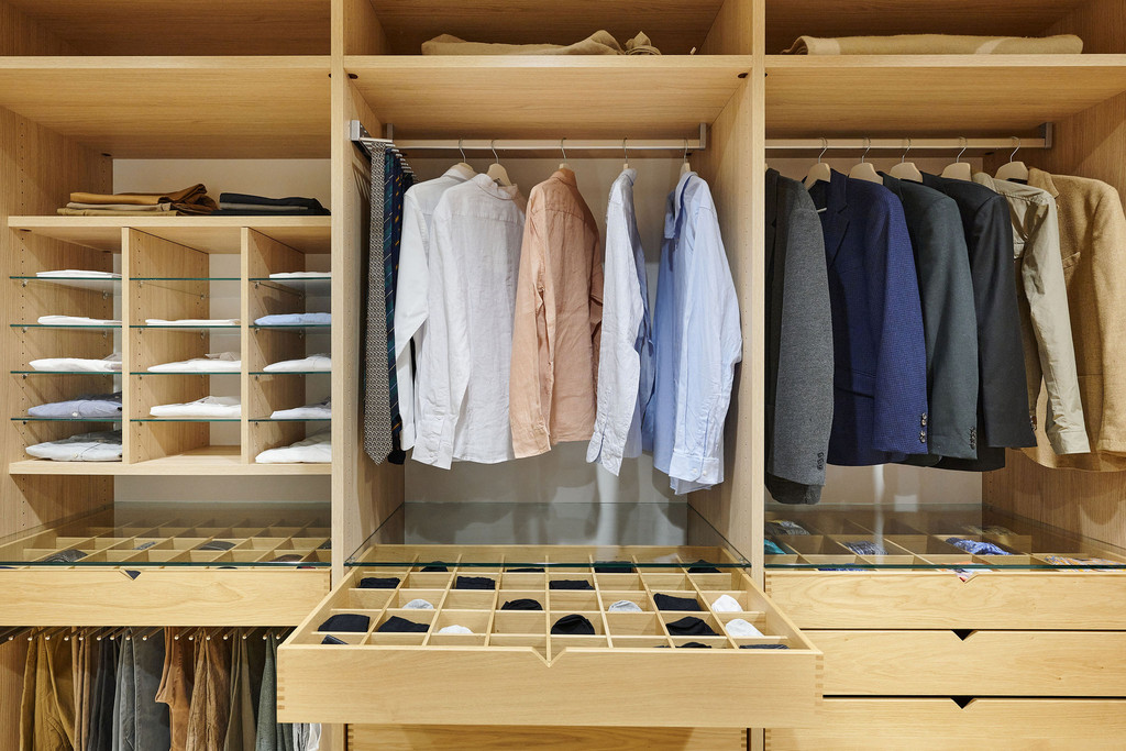 Dressing ouvert sur mesure avec penderies et tiroirs coulissants, exposé dans le showroom de Aartselaar