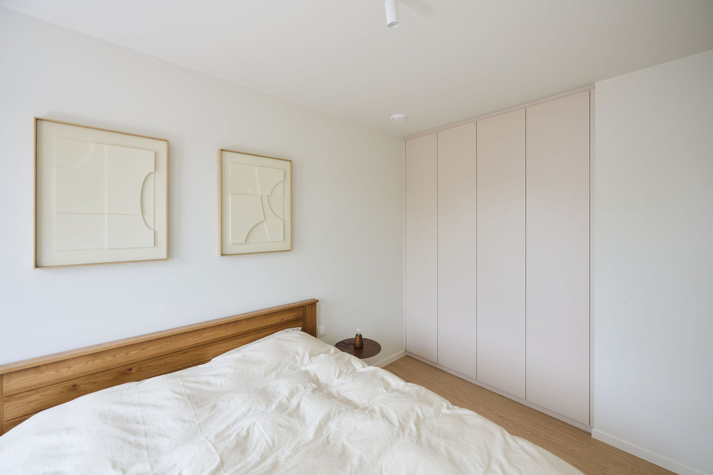 Armoire encastrée sur mesure dans une chambre lumineuse avec lit en bois et housse de couette blanche
