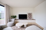 Meuble TV sur mesure avec armoires basses et plateau foncé dans un salon moderne aux tons beiges
