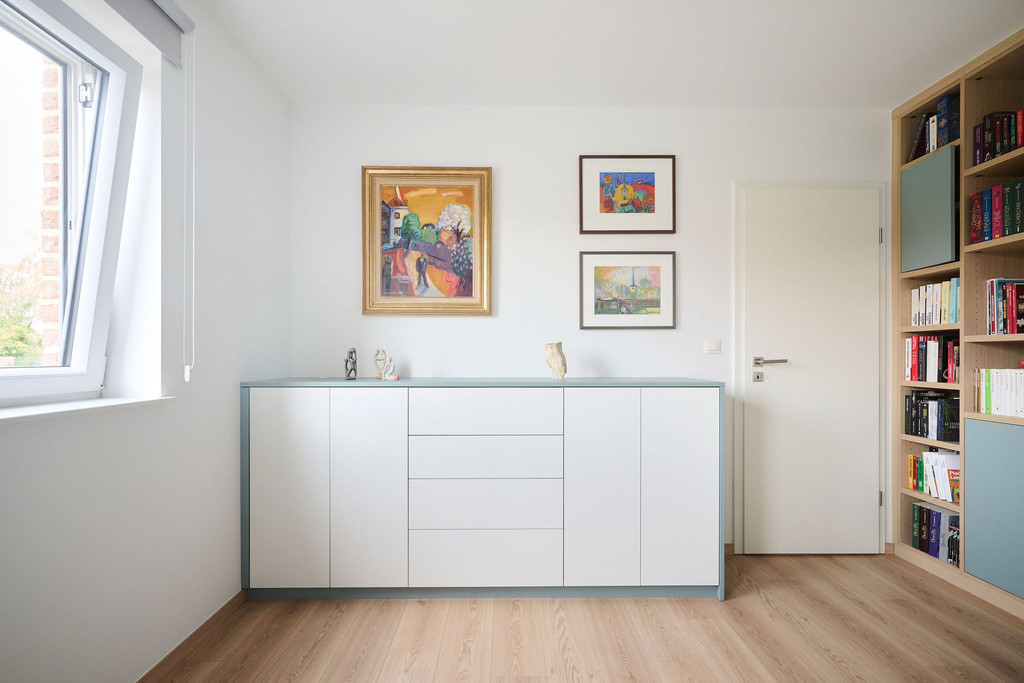 Lage witte opbergkast op maat in een slaapkamer met greeploze deuren, geïntegreerde lades en een lichtblauw bovenblad