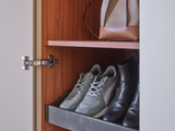 Tiroir ouvert avec baskets et bottines dans une armoire vestiaire en bois avec tablette rose