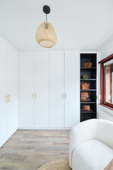 Dressing fermé sur mesure avec portes blanches et poignées dorées, accompagné d’étagères noires ouvertes pour le rangement des sacs à main.