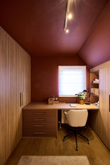 Bureau op maat onder schuin dak met lades, kast en werkplek bij het raam in warme slaapkamer