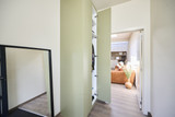Armoire vestiaire sur mesure vert clair avec porte ouverte et vue sur le salon