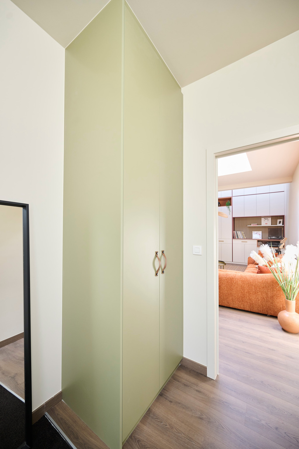Op maat gemaakte vestiaire in een nis, uitgevoerd in olijfgroene tint met lederen handgrepen