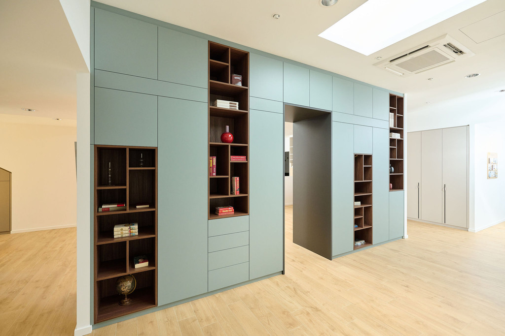 Blauwe multifunctionele ingebouwde boekenkast op maat met kasten en open nissen en dek over deur in Waver