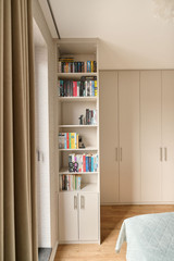 Petite bibliothèque intégrée dans un dressing sur mesure avec étagères ouvertes et rangements fermés, offrant un espace pratique et esthétique, réalisé par Camber