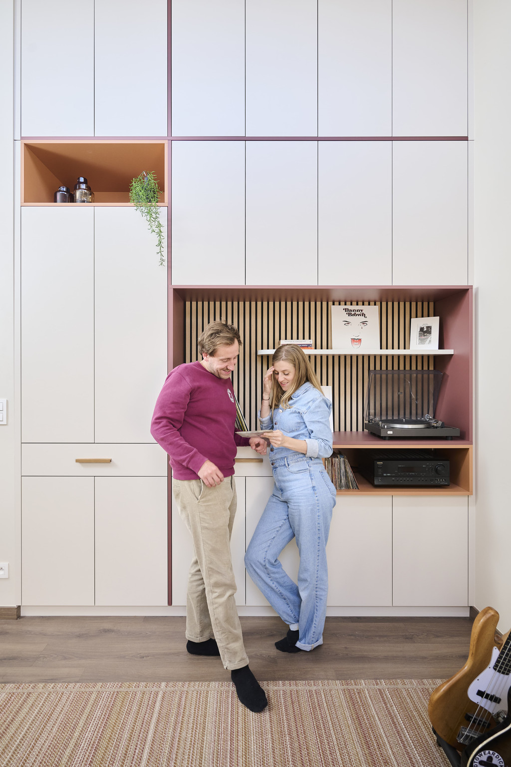 Couple devant une armoire blanche sur mesure avec coin musique panneau à lattes et amplificateur intégré