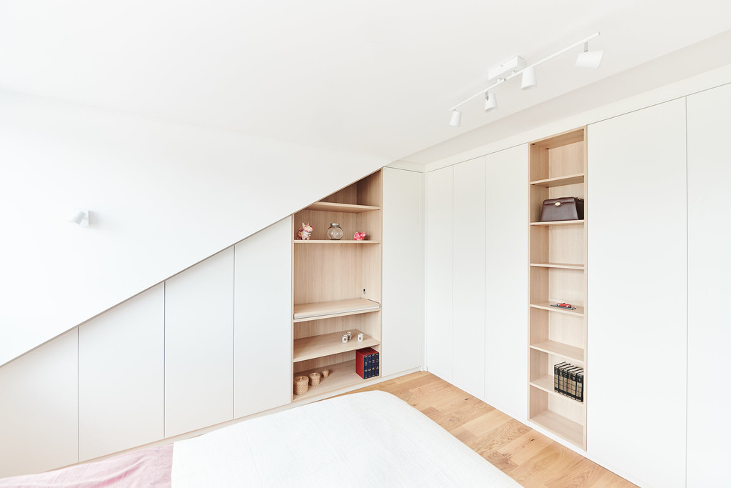 Rangement sous pente avec étagères ouvertes et placard, optimisé pour un espace sous toit.