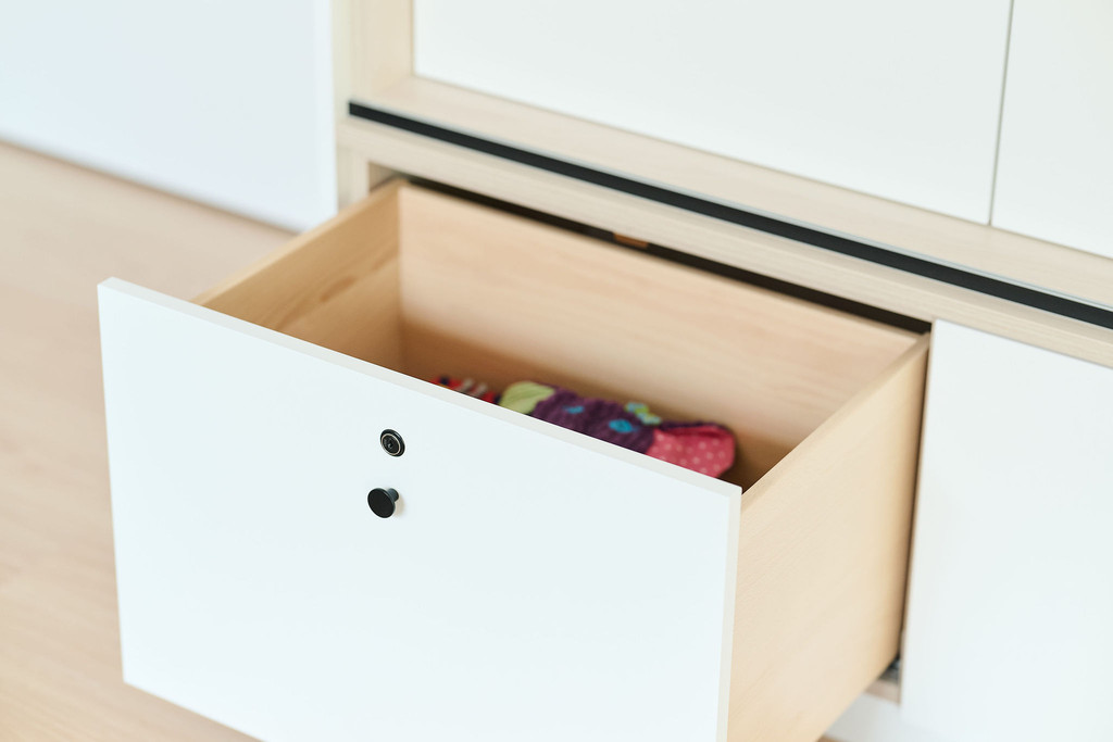 Tiroir en bois ouvert avec jouets dans un meuble sur mesure blanc au salon