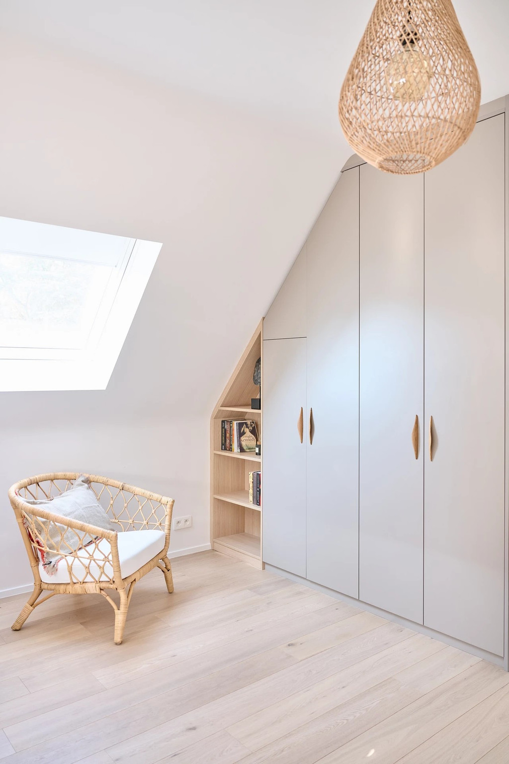 Rangement sous pente avec placard et étagères ouvertes, offrant une solution de rangement pratique dans un espace sous toit.