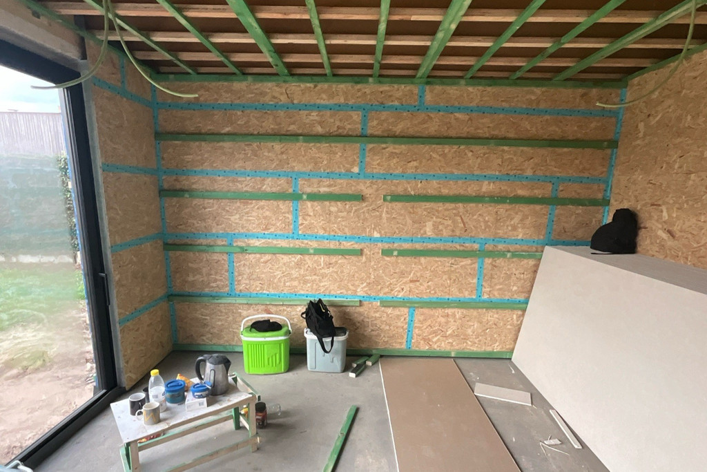 Espace intérieur brut avec murs en OSB et structure en bois visible en phase de chantier