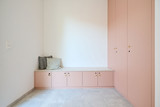 Armoire basse rose avec banc et coussins dans un coin vestiaire moderne