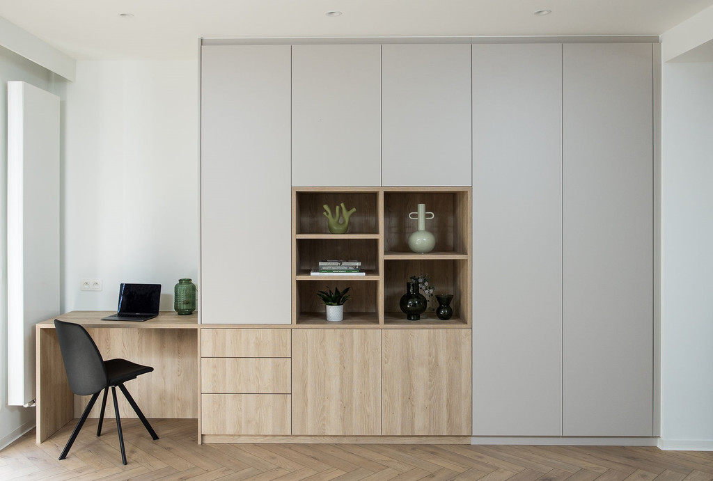 Bureau sur mesure avec rangements fermés et niches ouvertes en bois clair et blanc, décoré avec des objets et plantes.