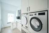 Op maat gemaakte wasruimte met wasmachine en droger, inclusief opbergruimte voor wasmanden.