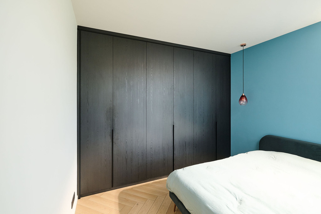 Dressing noire sur mesure avec poignées intégrées dans une chambre moderne