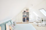 Dressing sur mesure intégré sous pente avec étagères ouvertes et penderie pour vêtements, avec un éclairage moderne.