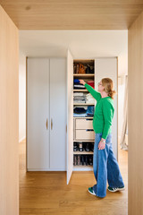 Placard sur mesure utilisé comme séparateur de pièce avec niches ouvertes, tiroirs et penderie dans une chambre