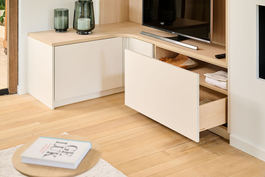 Open lades van een hoek-tv-meubel op maat met beige fronten en licht houten interieur