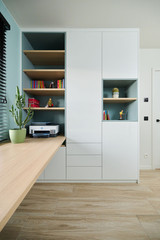 Bureau sur mesure avec rangements fermés et étagères ouvertes en bois, imprimante intégrée et niches décoratives vertes.