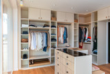 Dressing ouvert blanc sur mesure avec îlot central en bois et éclairage intégré dans une chambre moderne