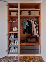 Armoire ouverte sur mesure avec finition bois tiroirs penderie et range-chaussures dans le hall d’entrée