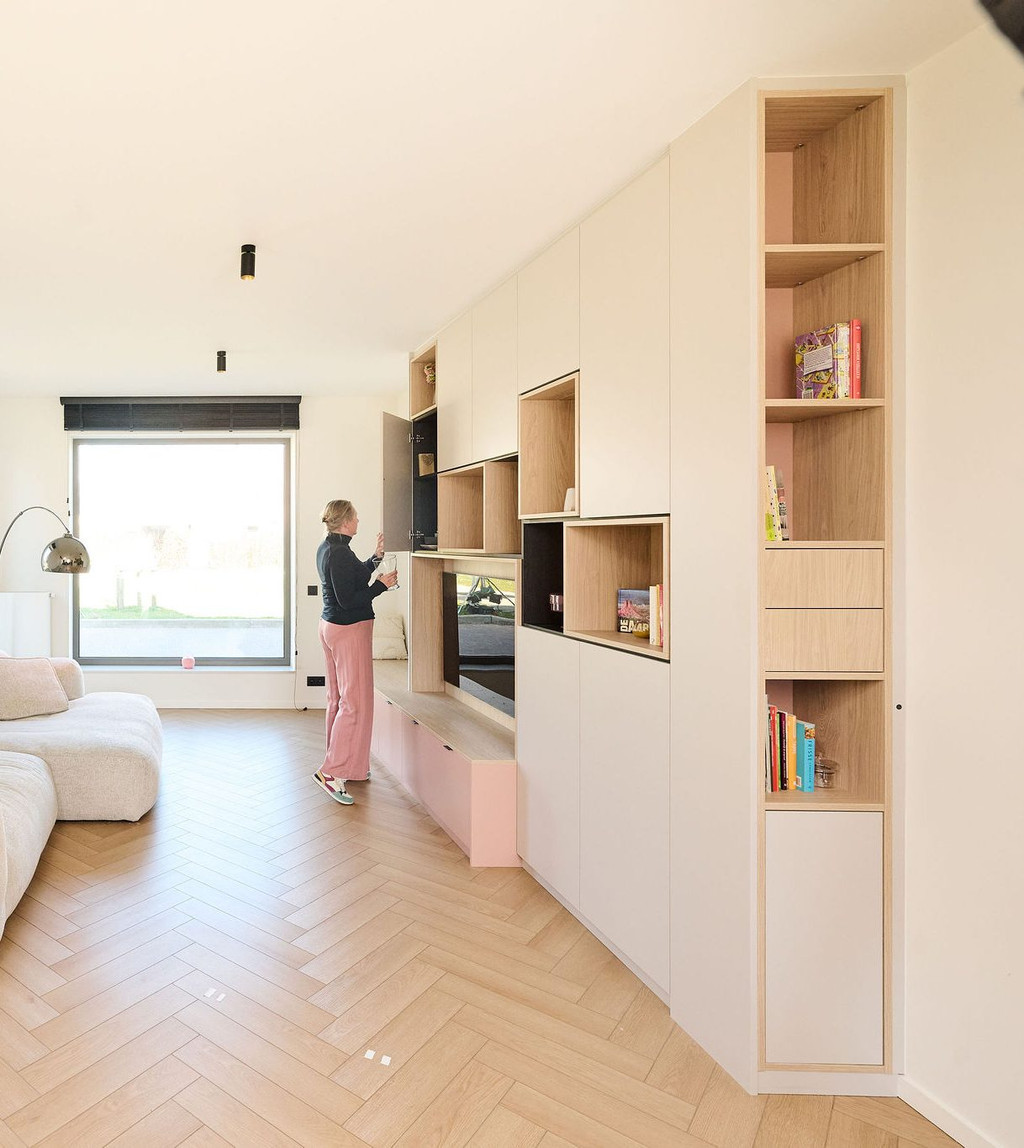 Meuble TV sur mesure avec banc intégré, niches ouvertes en bois clair et rangements fermés dans un salon lumineux