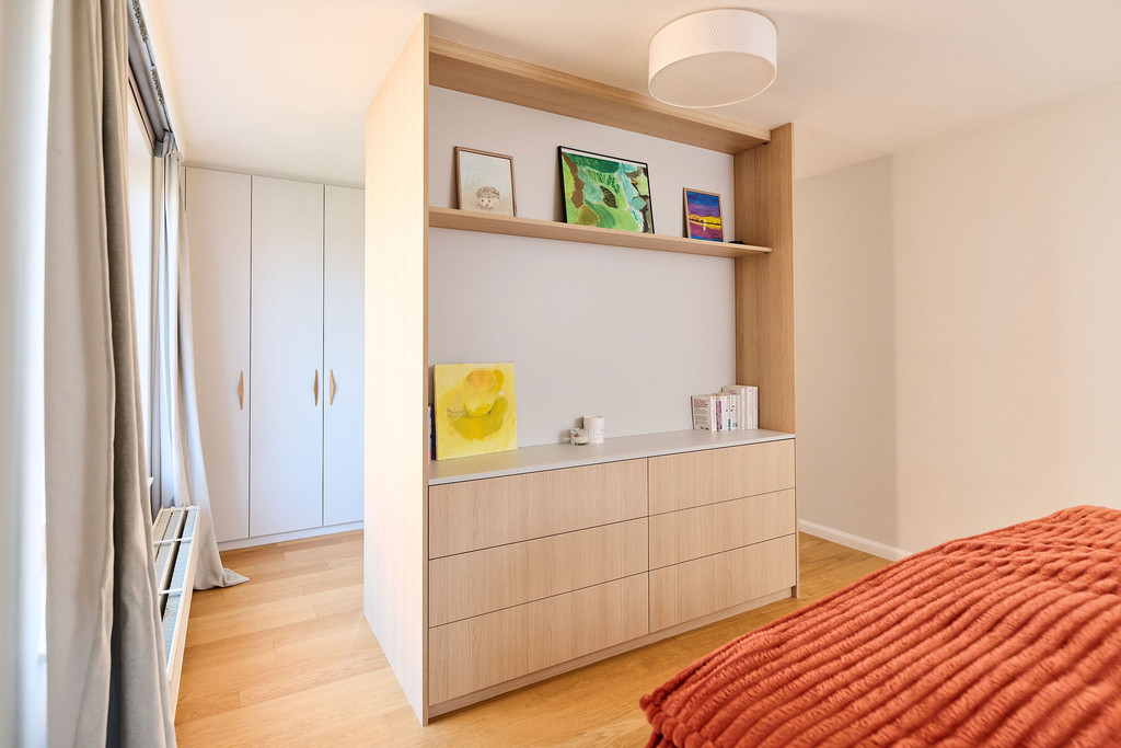 Placard sur mesure utilisé comme séparateur de pièce avec tiroirs, niche ouverte et rangements dans une chambre