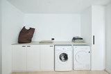 Buanderie moderne avec machine à laver, sèche-linge, étagère de rangement et panier à linge