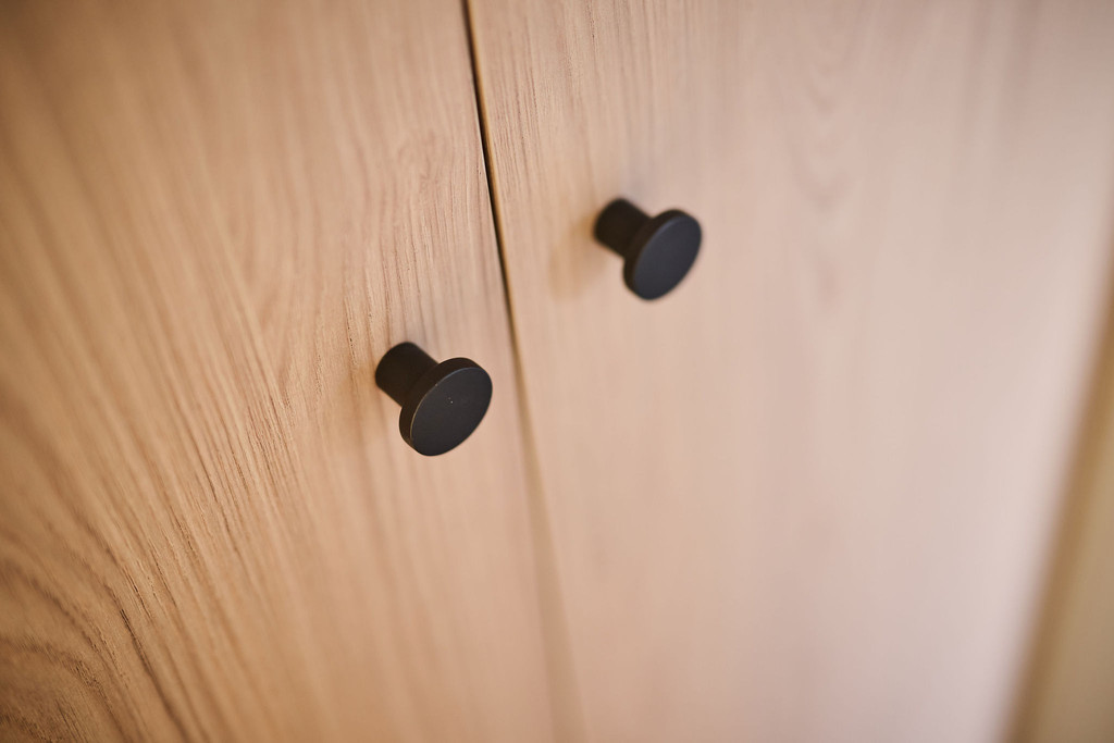 Close-up van twee ronde zwarte knoppen op houten kastdeuren van op maat gemaakte vestiairekast