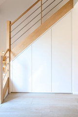 Rangement sous escalier sur mesure avec portes blanches et escalier en bois clair