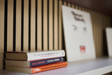 Détail d’un panneau à lattes en bois avec étagère blanche contenant des livres et objets décoratifs