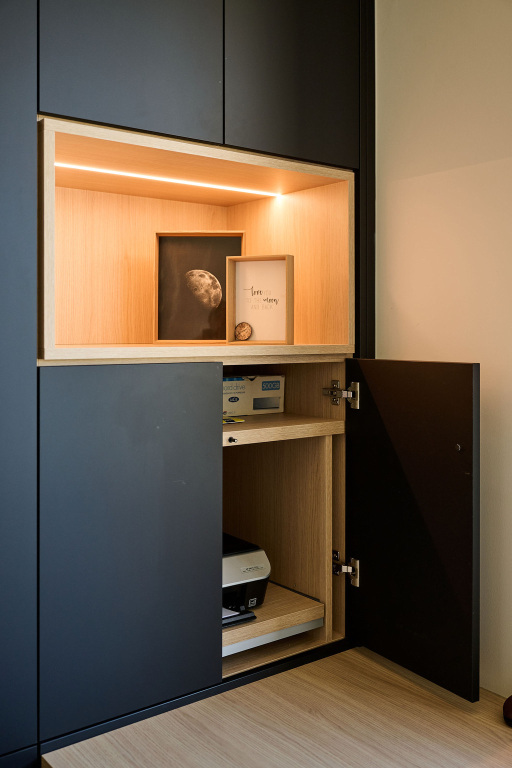 Armoire de bureau noire sur mesure avec niche en bois éclairée par LED et compartiment pour imprimante avec portes fermées