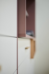Détail d’un meuble blanc sur mesure avec finition sans poignée et niche en vieux rose