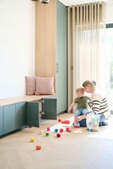 Maman jouant avec son enfant devant un banc de rangement vert avec portes ouv