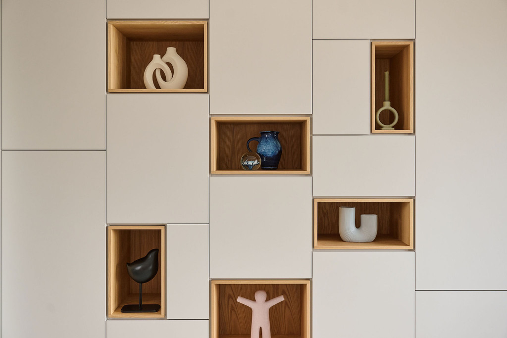 Détail d’un placard sur mesure avec niches ouvertes en finition bois, mettant en valeur des objets décoratifs dans un design moderne et structuré, réalisé par Camber