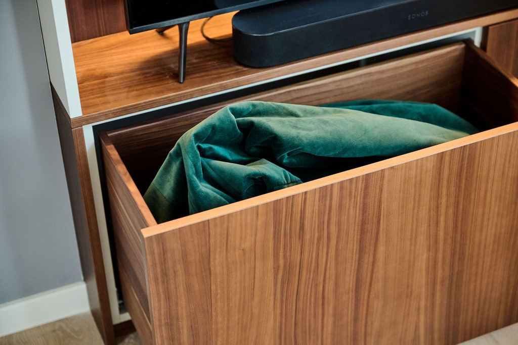 Laadkast op maat met open vakken en een opgerolde deken in de lade in de woonkamer.