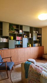 Open boekenkast op maat in kaki en hout, met asymmetrische indeling en decoratieve accenten