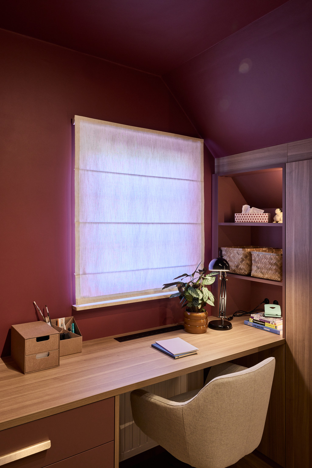 Bureau op maat met lades en open vakken onder een raam in een warme slaapkamer