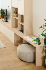 Meuble sur mesure clair avec bureau intégré, étagères ouvertes et pouf dans un salon