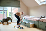 Homme ouvrant un tiroir de rangement sous un lit d’enfant vert sur mesure dans une chambre lumineuse