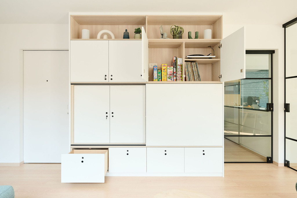 Meuble blanc ouvert avec jeux de société et livres visibles dans le salon