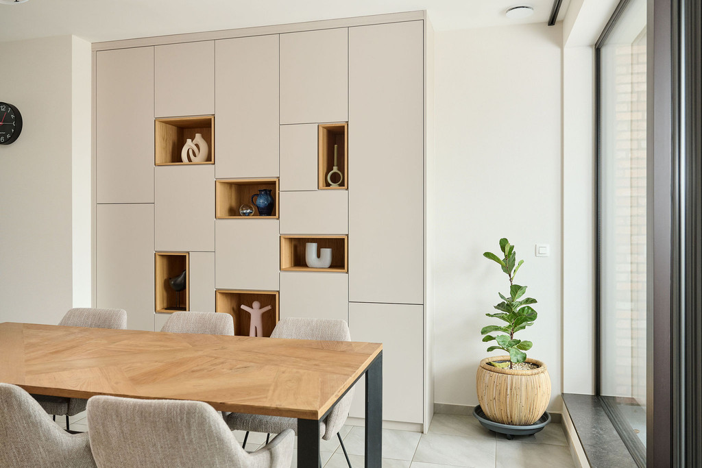 Placard sur mesure avec niches ouvertes en finition bois et rangements fermés, intégré dans une salle à manger lumineuse avec table et plante, réalisé par Camber