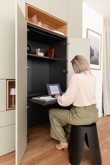 Bibliothèque sur mesure avec bureau escamotable intégré derrière des portes, offrant un espace de télétravail discret, ergonomique et parfaitement intégré au séjour