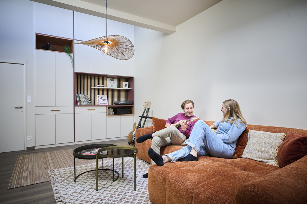 Salon cosy avec canapé orange, guitare et armoire sur mesure avec niche et vinyles
