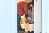 Vrouw haalt een trui uit een open lade van een maatkast in de vestiaire