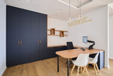 Espace de travail avec bureau et placard sur mesure aux portes foncées et accents bois en showroom
