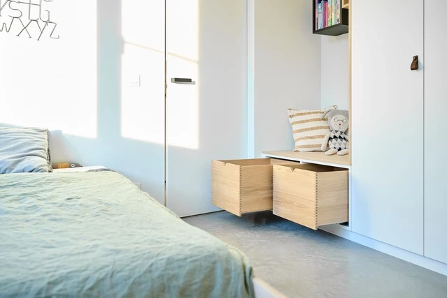 Meuble sur mesure avec des tiroirs et un coin lecture dans une chambre d'enfant.